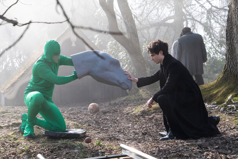 Morpheus (Tom Sturridge) touches a model head of Gregory the gargoyle.