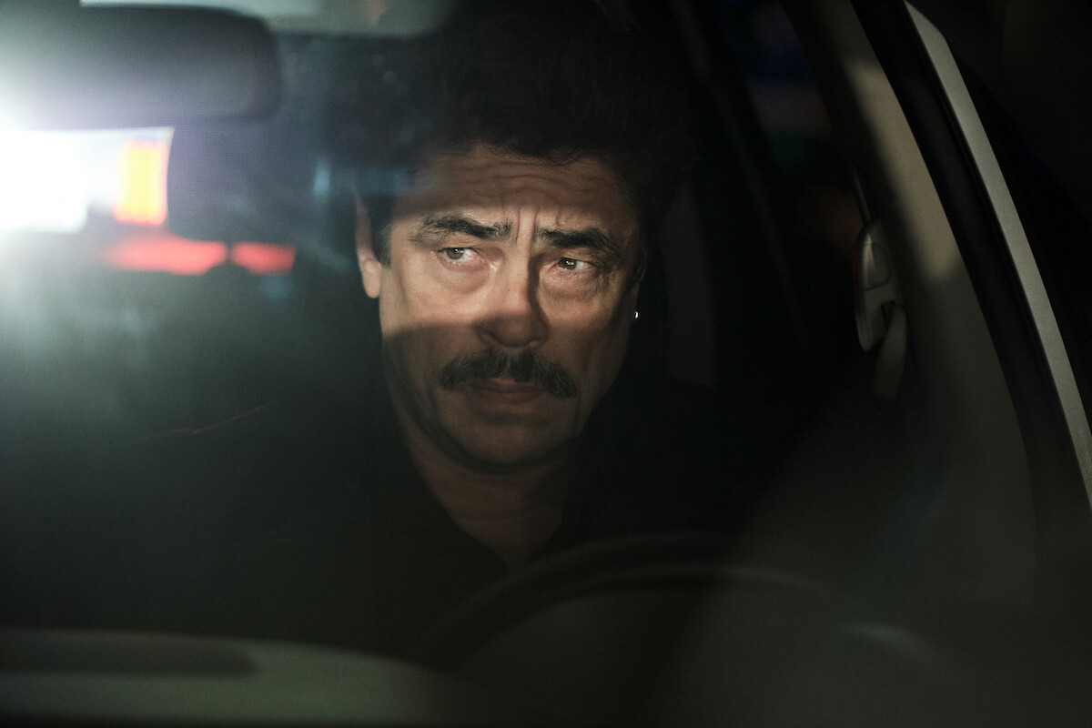 Benicio Del Toro sits in a car in a still from ‘Reptile.’