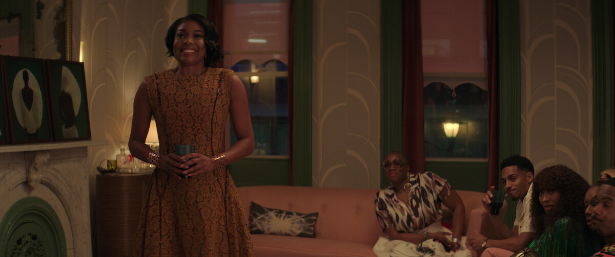Gabrielle Union hosts a dinner party in a brown lace dress in a still from ‘The Perfect Find.’