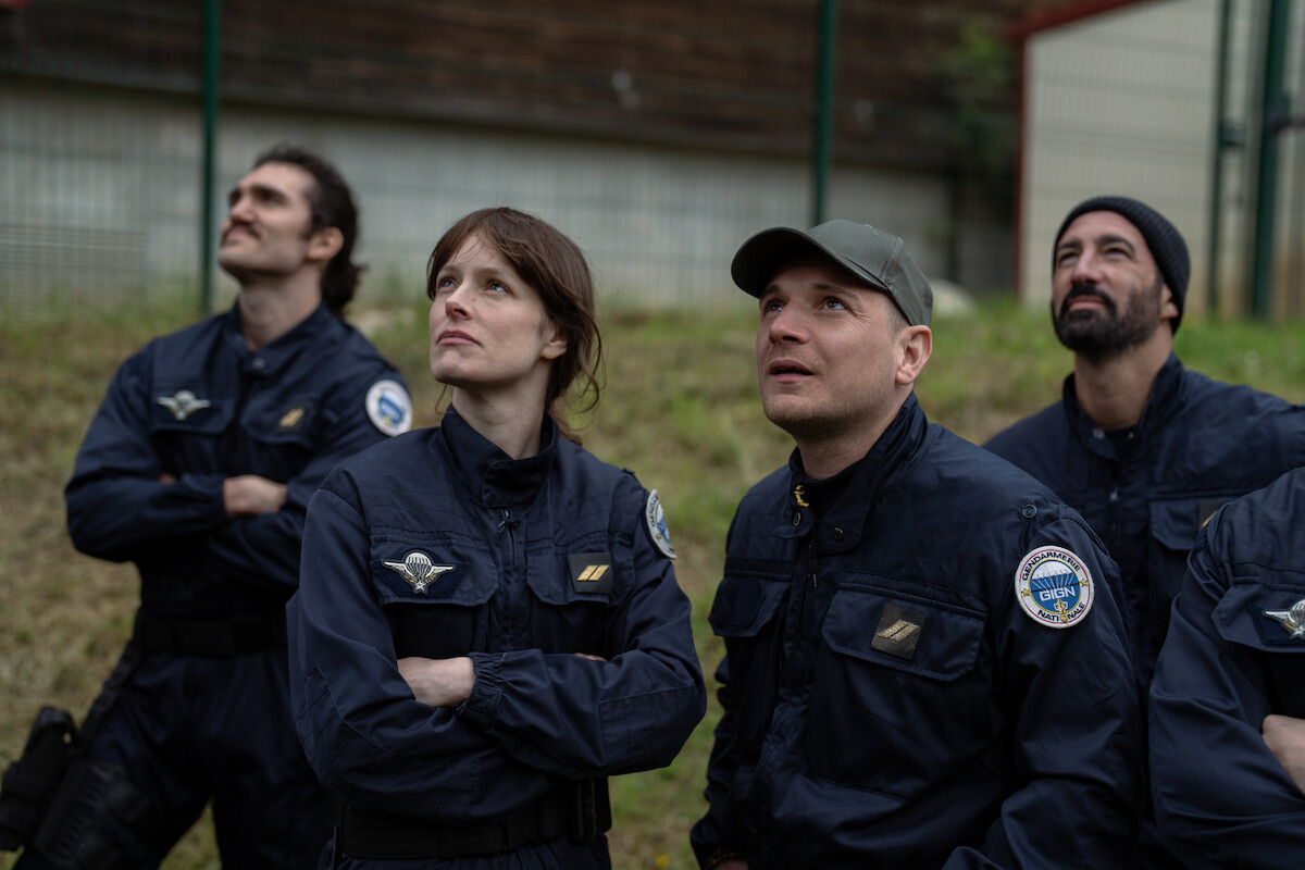 A group of four police officers in uniform, including Stéphane Caillard as Léo and Alexis Manenti as Nico, look toward the sky in an image from the film ‘Ad Vitam.’