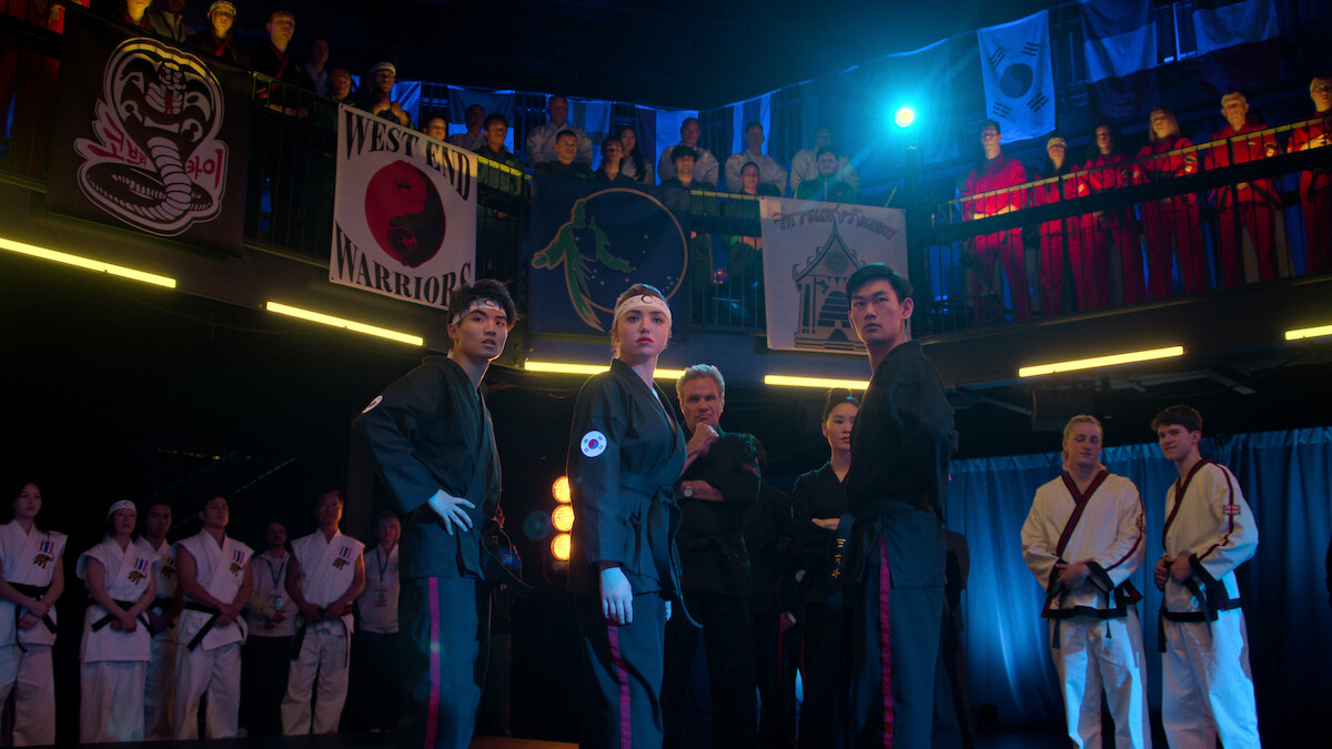 Brandon H. Lee as Kwon, Peyton List as Tory Nichols, Martin Kove as John Kreese, Alicia Hannah-Kim as Kim Da-Eun, and Daniel Kim as Yoon stand together at the Sekai Taikai tournament in Season 6 of ‘Cobra Kai.’