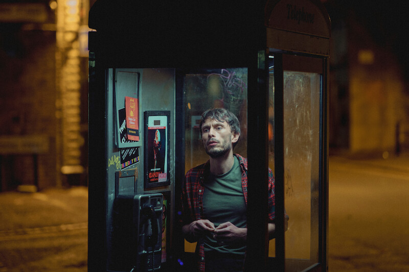 Richard Gadd as Donny Dunn stands in a phone booth at night in 'Baby Reindeer'
