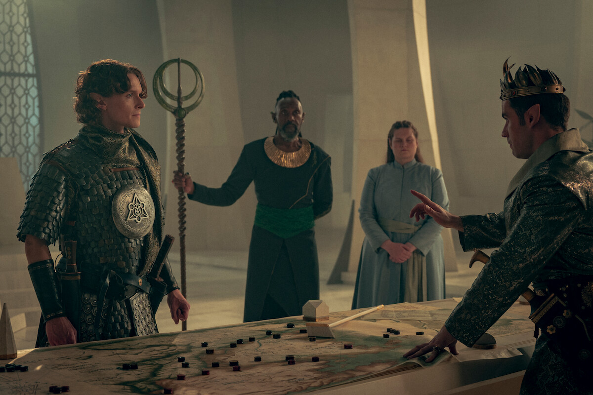 Character stand around a table discussing tactics.