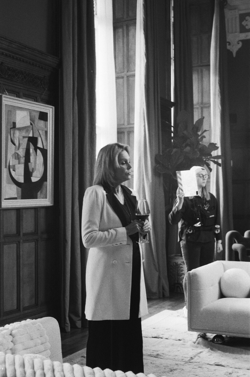Black-and-white image of Joanna Lumley as Judith Baker holding a glass of wine behind the scenes in Season 1 of 'Fool Me Once'