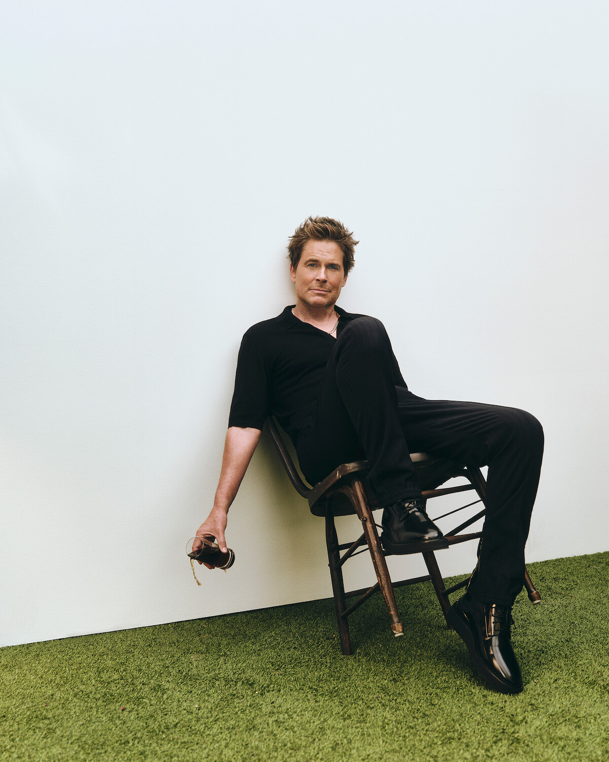 Rob Lowe leans back on a chair.