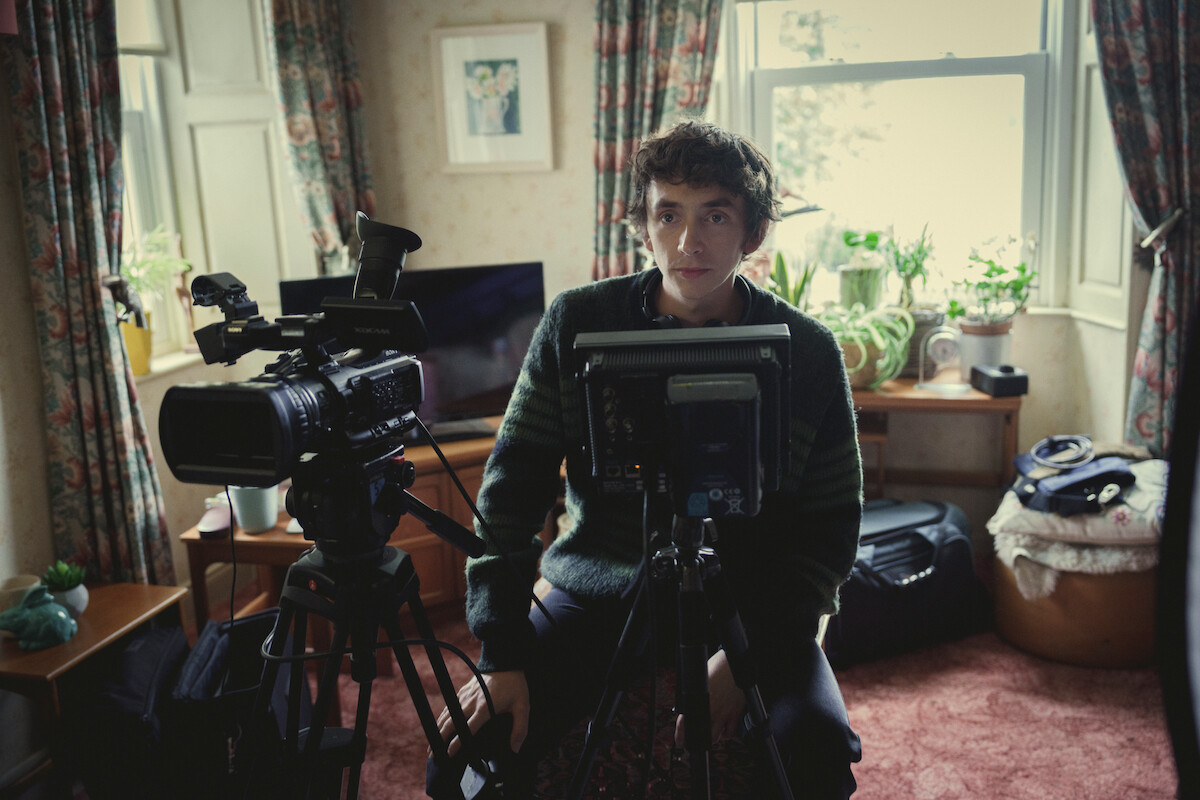 Samuel Blenkin as Davis in Black Mirror Season 6 sitting with camera equipment. 