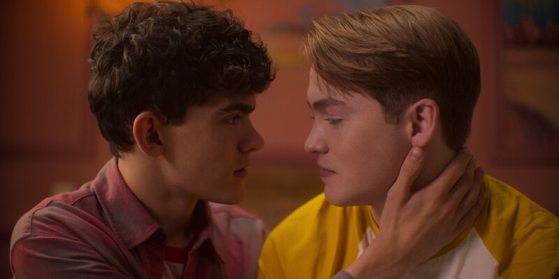 Two boys holding each other about to kiss
