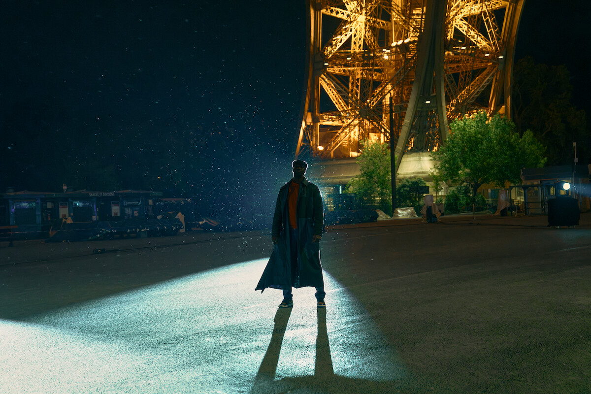 Um homem alto está no contraluz debaixo da torre Eiffel, deixando apenas sua silhueta à vista