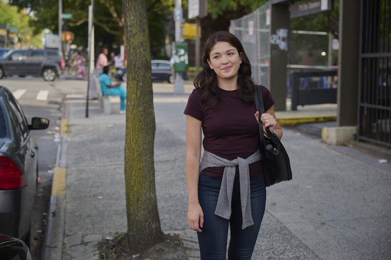A woman standing on the street in front of a tree