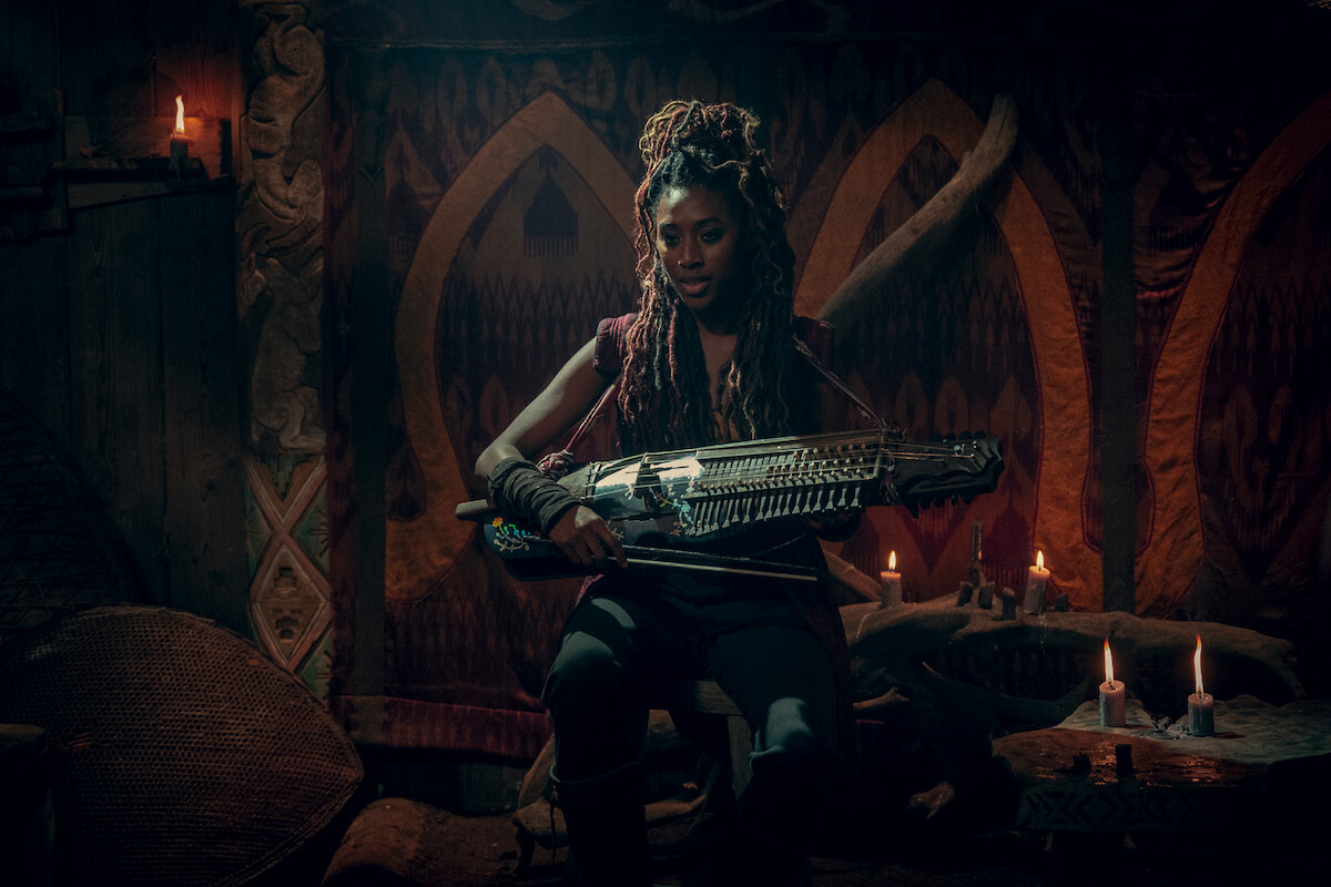 Éile (Sophia Brown) holding an instrument.