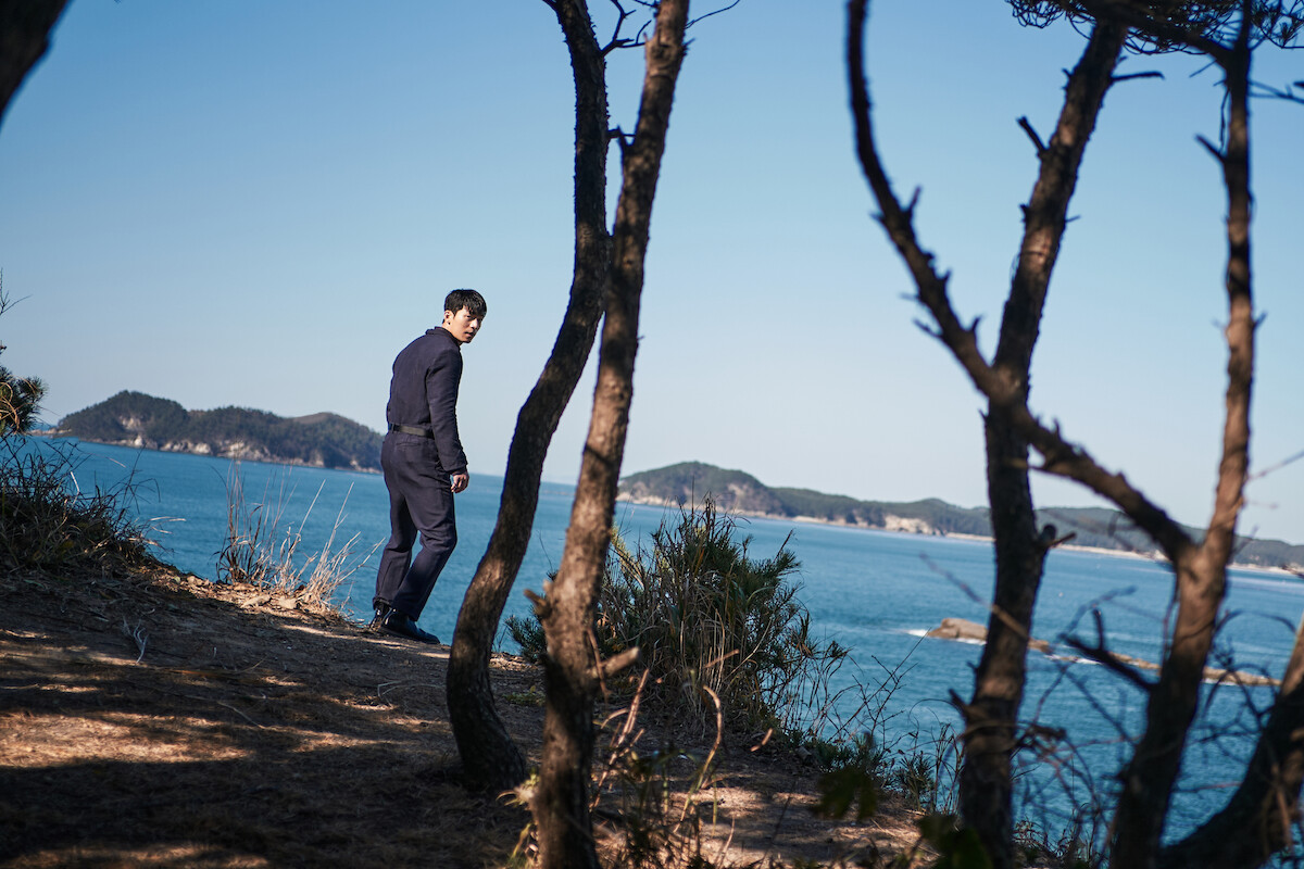 Wi Ha-jun as Hwang Jun-ho standing on a coastal cliff in ‘Squid Game’ Season 1.