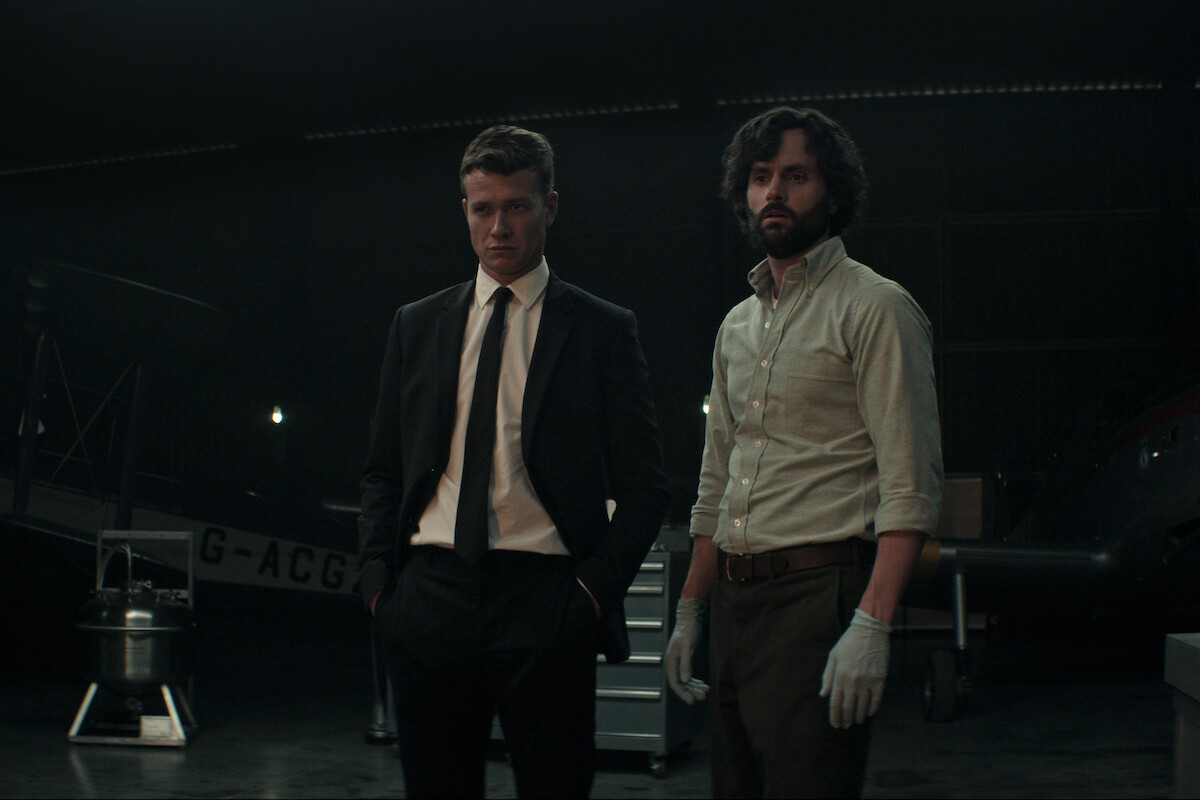 Ed Speleers as Rhys Montrose stands next to Penn Badgley as Joe Goldberg