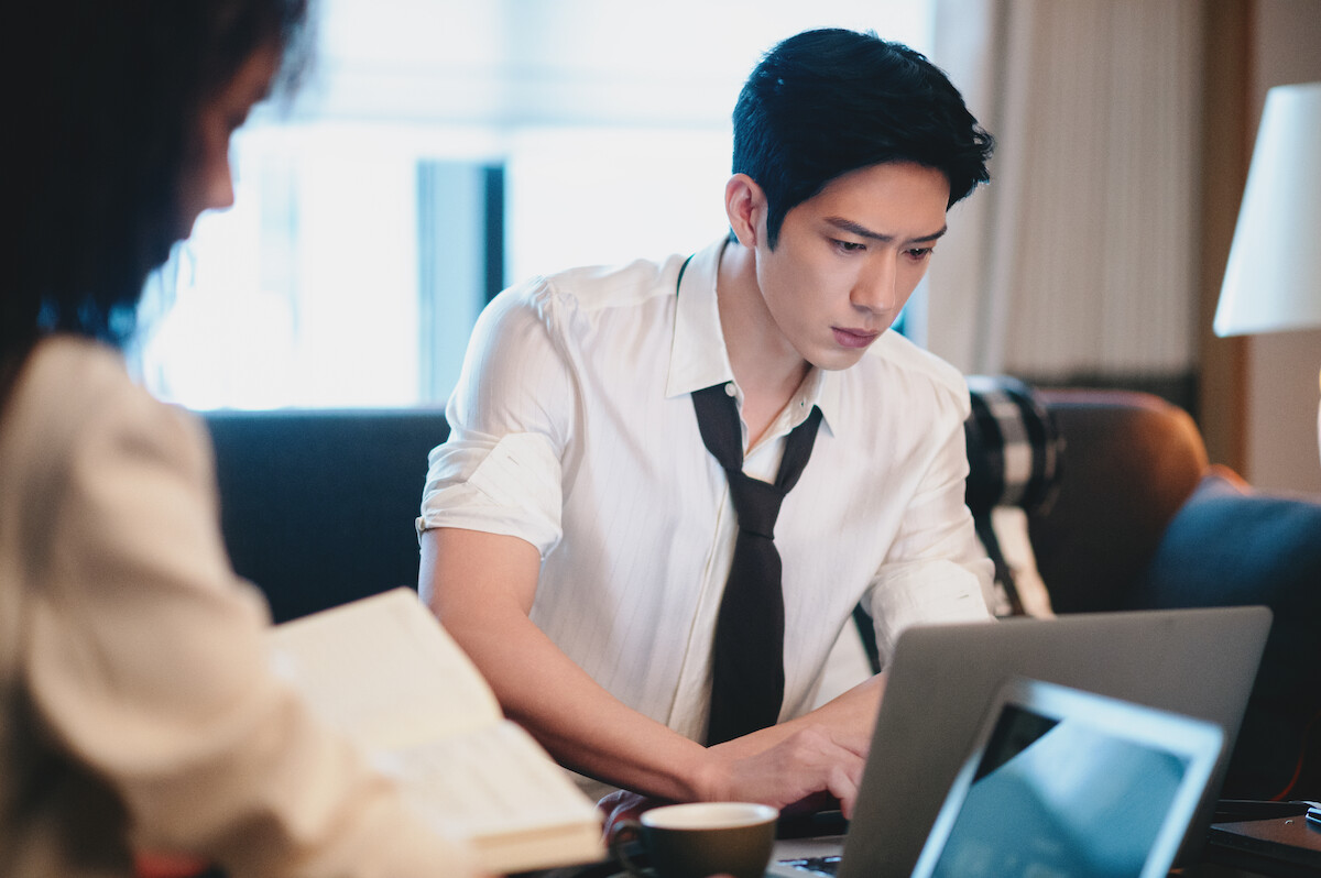 Um homem chinês trabalha em um notebook, em uma sala