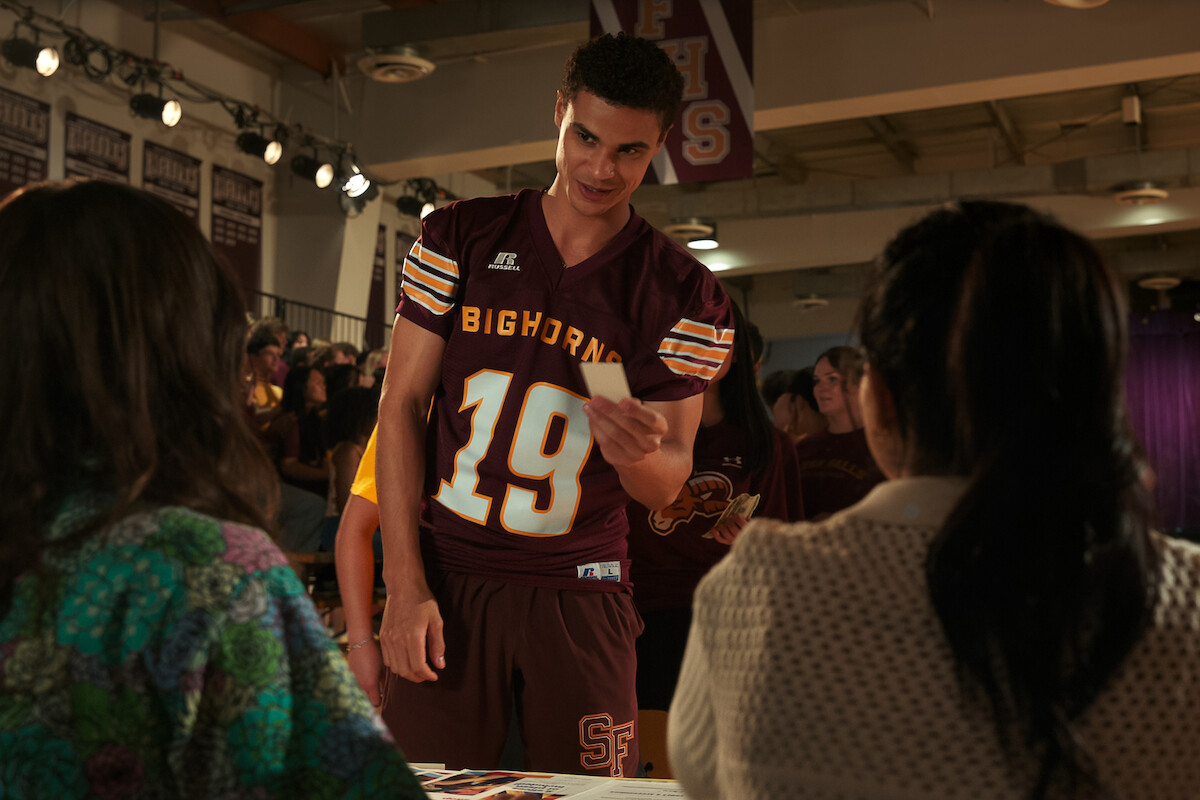 Kolton Stewart as Dylan wears a football jersey in a school gymnasium in ‘My Life with the Walter Boys’ Season 2.