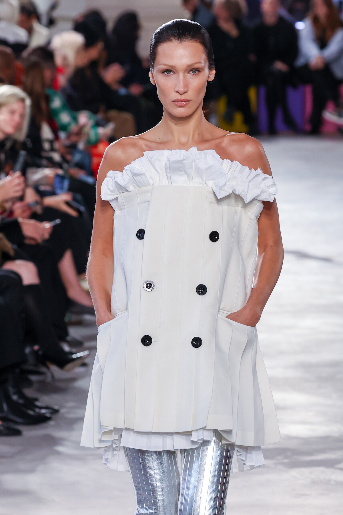Bella Hadid walks the runway in a white and silver garment. 