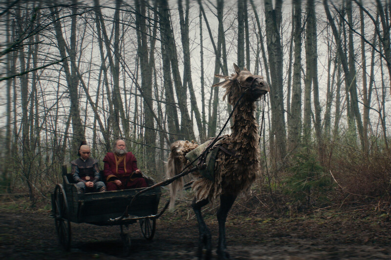 Dallas Liu as Prince Zuko and Paul Sun-Hyung Lee as Iroh ride in a chariot pulled by a large creature in season 1 of 'Avatar: The Last Airbender'