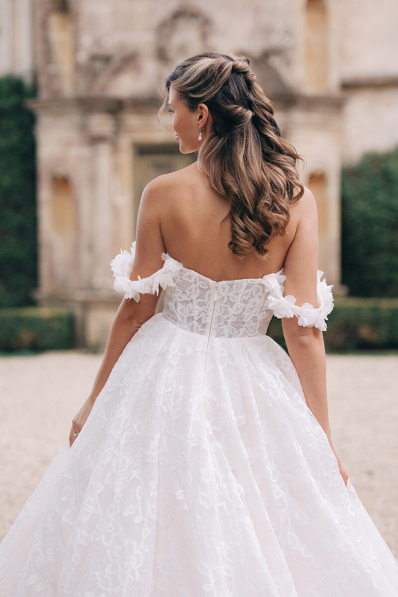 Woman in bridal dress looks over her shoulder.