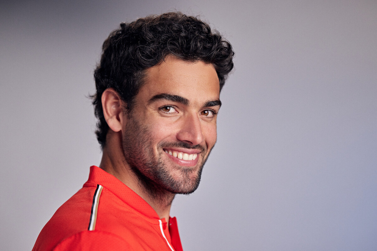 Matteo Berrettini smiles in a red jersey.