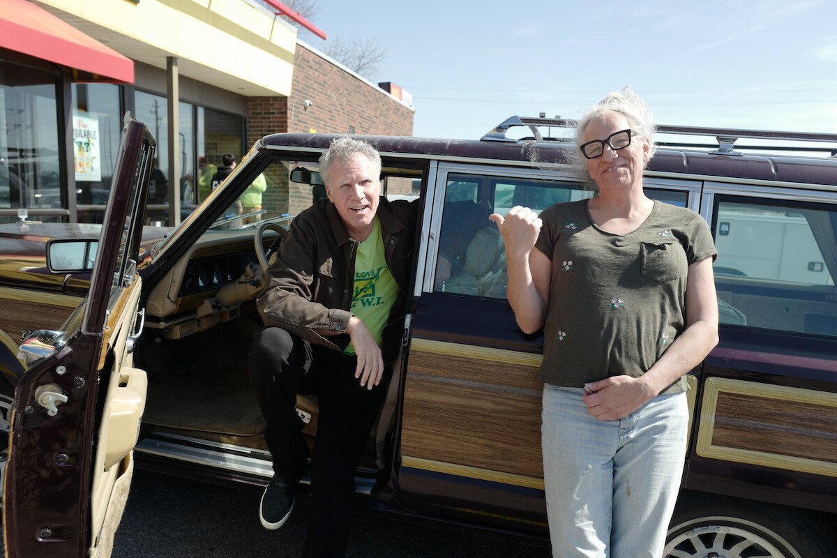 Will Ferrell and Harper Steele hand outside of their vehicle while parked in a lot on their cross-country roadtrip.