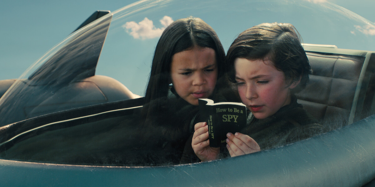 Everly Carganilla as Patty Tango-Torrez and Connor Esterson as Tony Tang-Torrez read ‘How to Be a Spy’ in 'Spy Kids: Armageddon.'