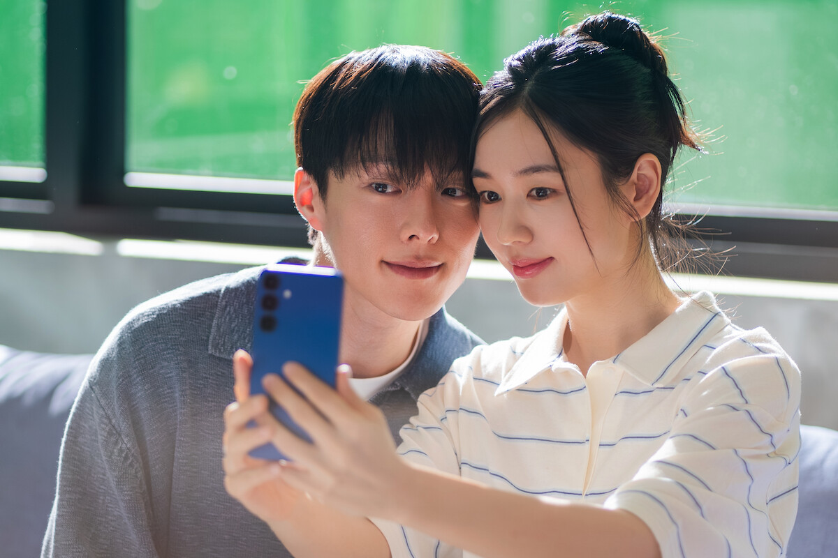 Um homem e uma mulher, ambos coreanos, tiram uma selfie com um celular