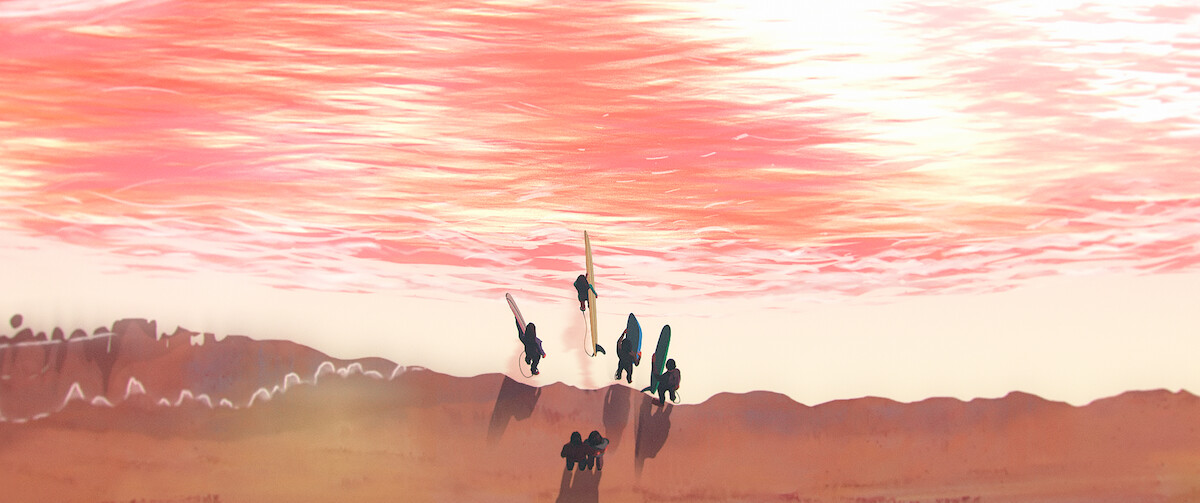 A group of surfers enter the ocean in an overhead shot with the slightly choppy surface of the ocean reflecting hues of pink, orange, and yellow with a sepia tone appearance to the scene.
