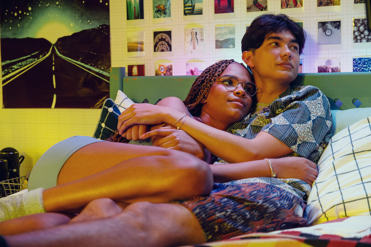 Yasmin Finney as Elle and Will Gao as Tao cuddle together in bed in Tao’s room in Season 3 of ‘Heartstopper.’