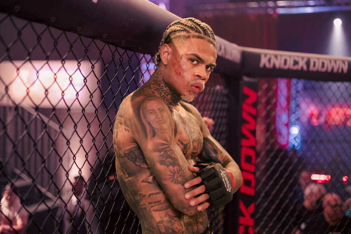 Lutador de MMA interpretado por MC Cabelinho repousa na grade de um ringue