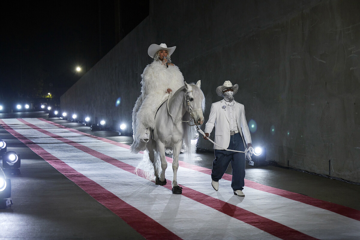 Beyonce riding on a white horse down a red and white striped runway during the Christmas Day NFL halftime show.