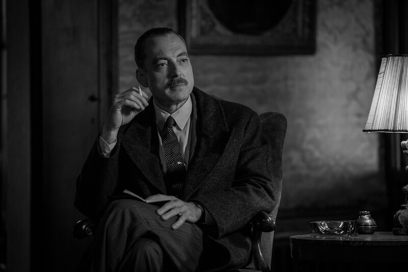 Maurizio Lombardi as Inspector Ravin sits in a dimly lit room in 'Ripley'
