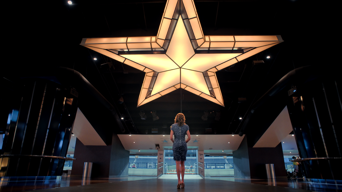 A woman stands under the Dallas Cowboys star inside AT&T Stadium.