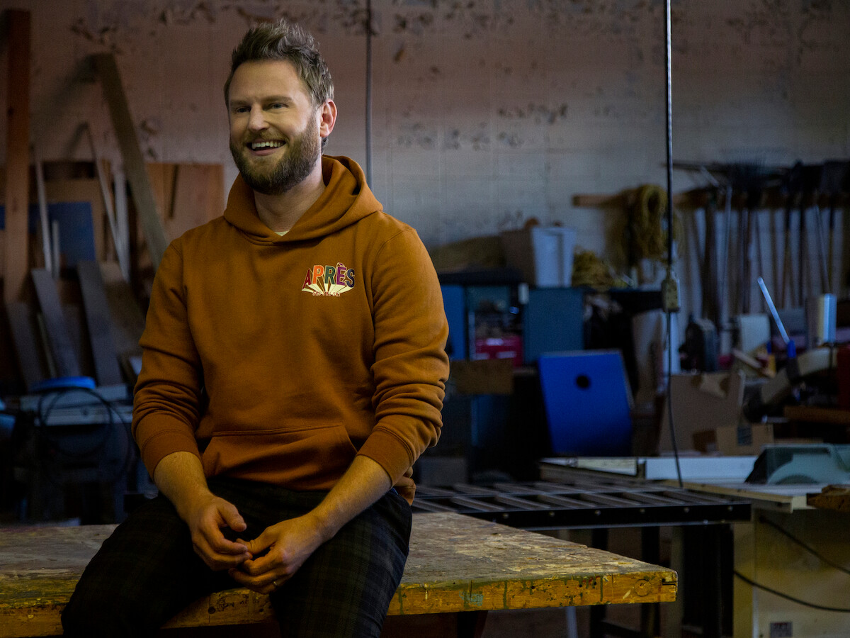 A man in a sweatshirt sitting on a table