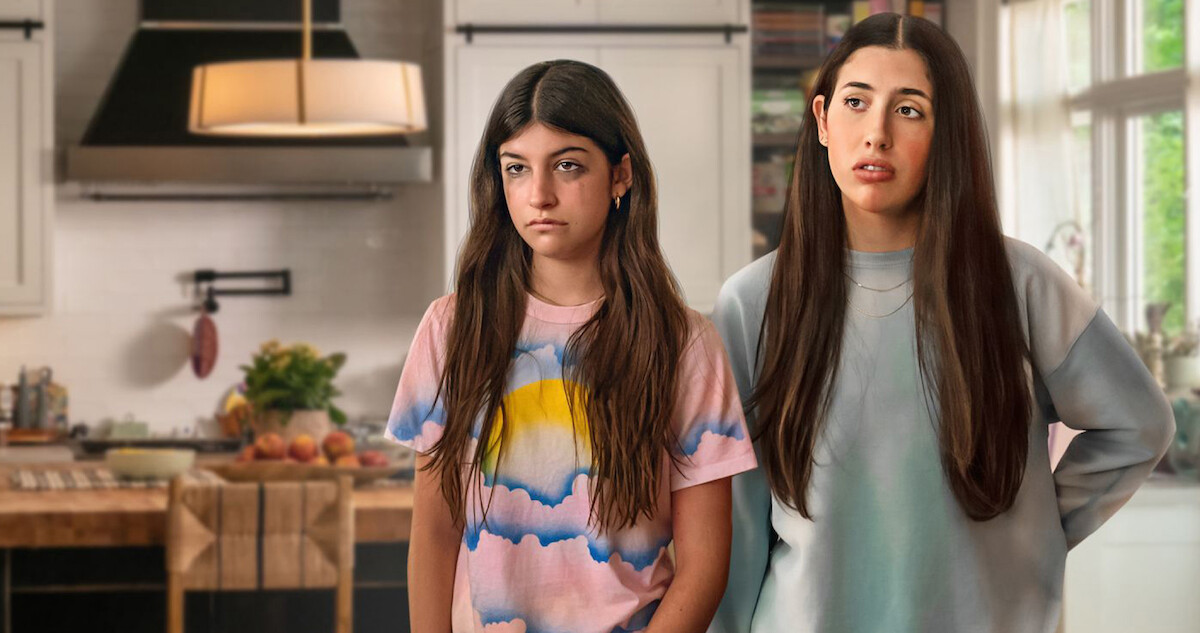 Stacy (Sunny Sandler) and Lydia (Samantha Lorraine) standing in a living room