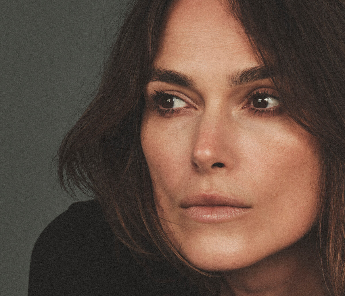 Keira Knightley wears a black top and looks off in the distance.