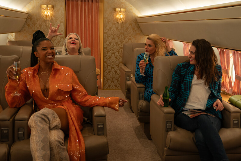 Renée Elise Goldsberry as Wickie, Paula Pell as Gloria, Busy Philipps as Summer, and Sara Bareilles as Dawn sit on a private plane together in Season 3 of 'Girls5eva'