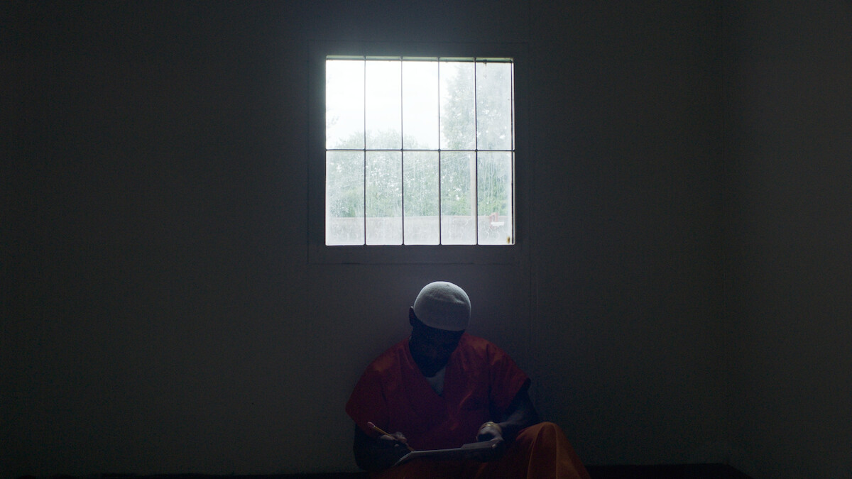 Keith Sweptson writes with a pencil and sits by a window.