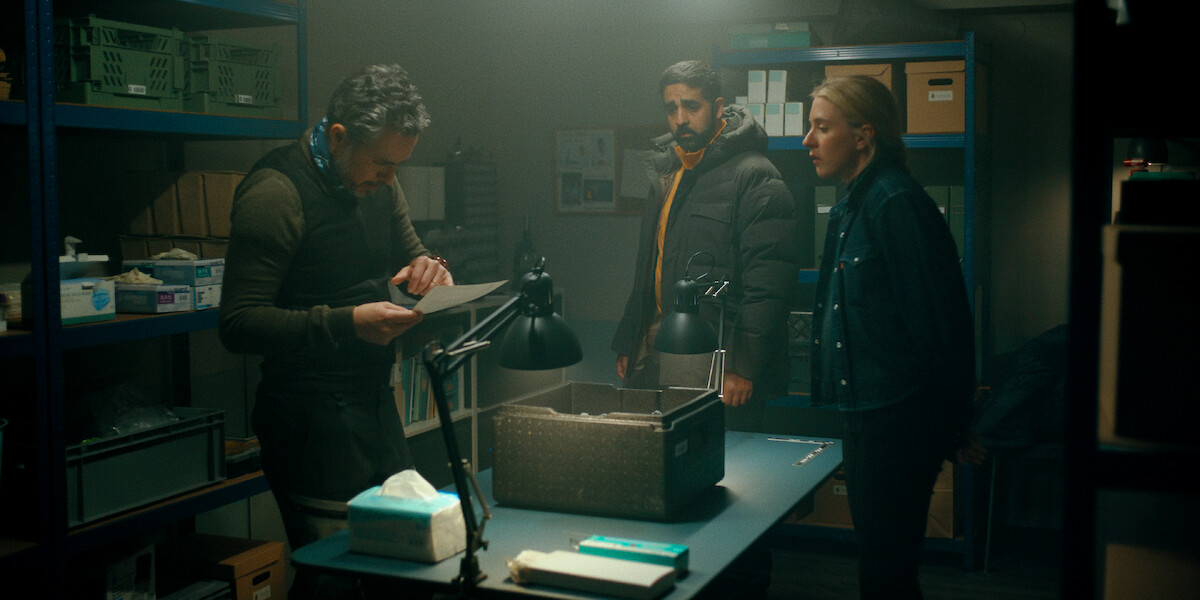 Carla Sehn and Kardo Razzazi look on as a man surveys a document in an image from ‘The Åre Murders.’