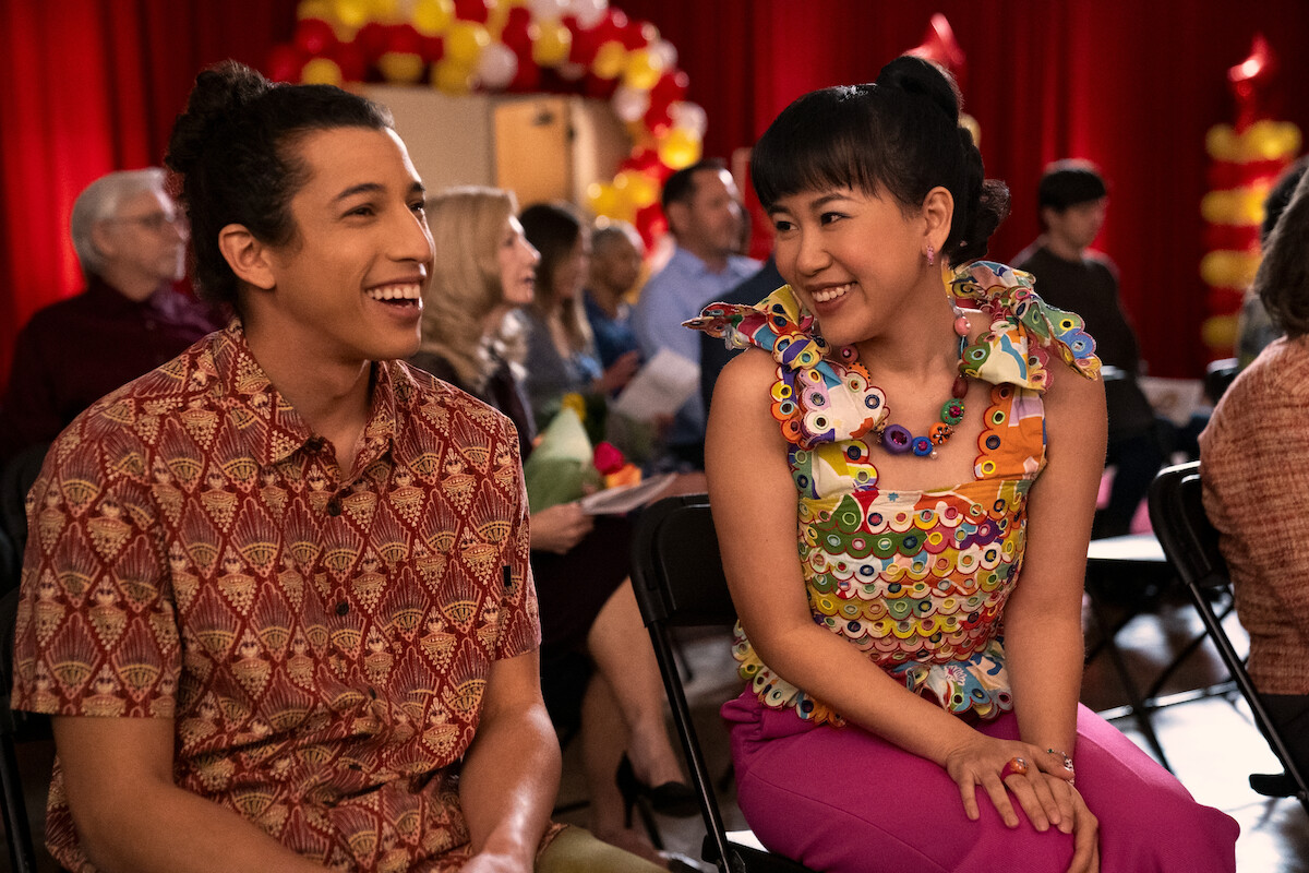 Benjamin Norris as Trent and Ramona Young as Eleanor Wong sit together smiling in ‘Never Have I Ever’ Season 3. 