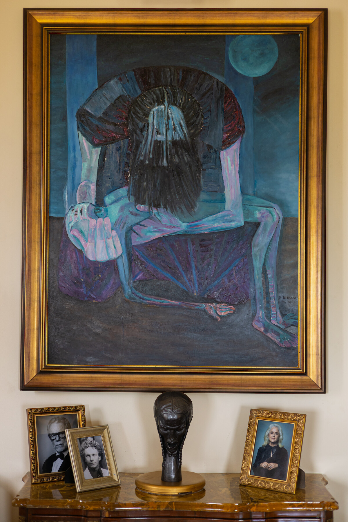 Um grande quadro azul mostra uma figura adulta curvada sobre uma figura infantil, cercadas por uma moldura dourada