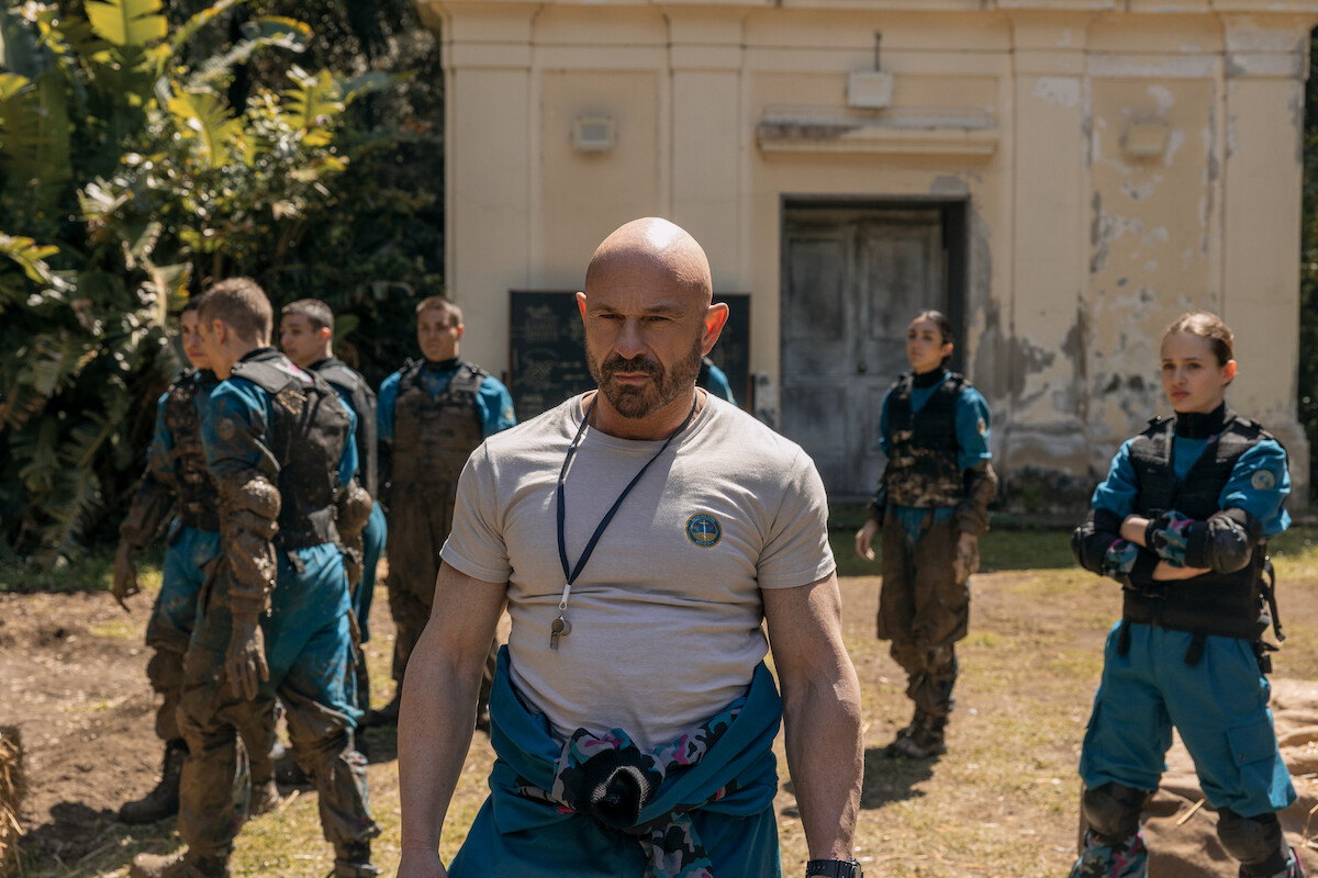 Homem careca e musculoso lidera um exercício militar no internato da série ‘Minerva’