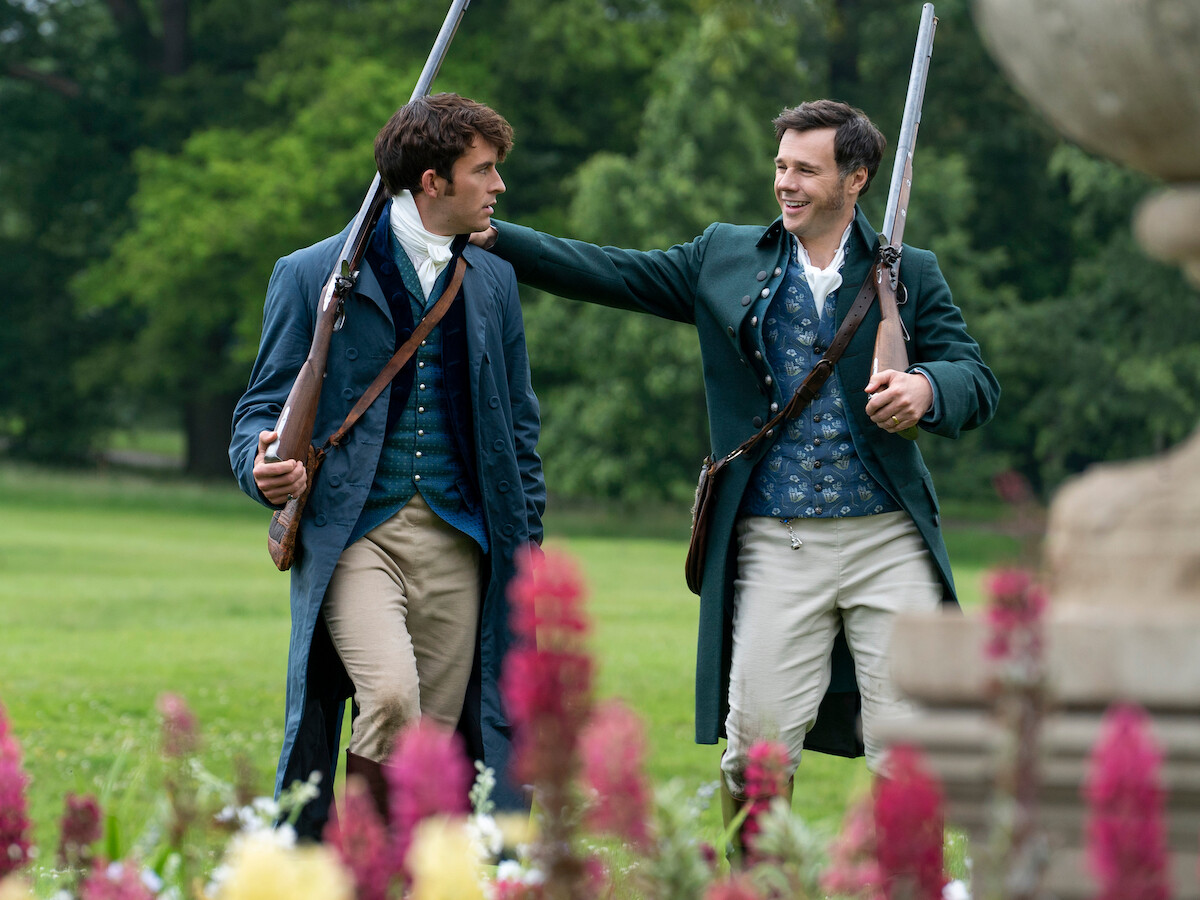 Edmund pats Anthony Bridgerton on the back,while both are holding rifles.
