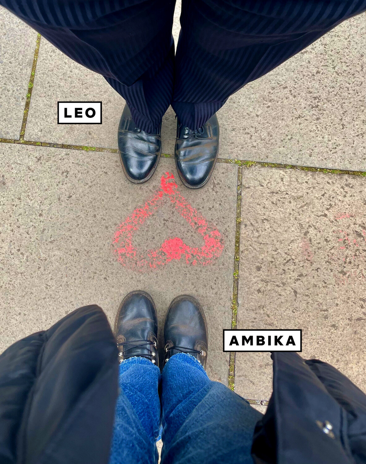 A top-down view of Leo Woodall and Ambika Mod’s feet facing each other on a sidewalk. A red heart is spray-painted on the ground between them.