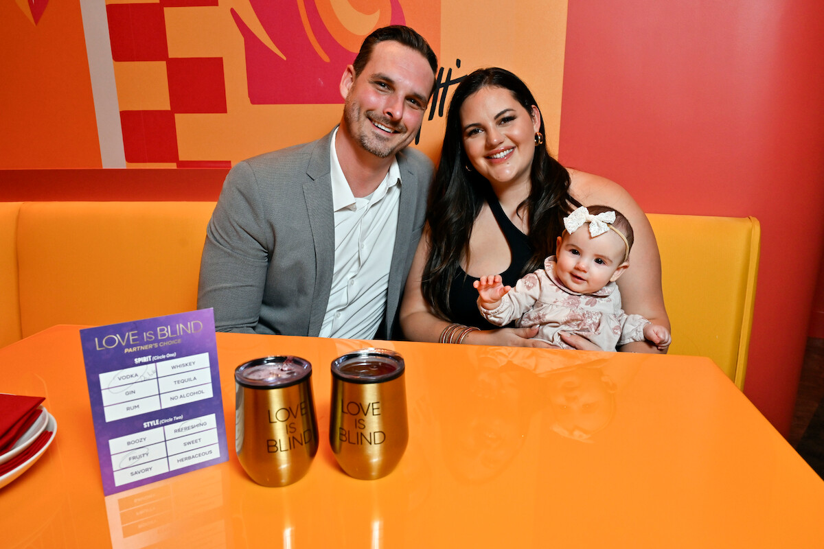 Brennon Lemieux, Alexa Lemieux, and Vienna Lemieux sit behind a table with two ‘Love Is Blind’ cups in front of them.