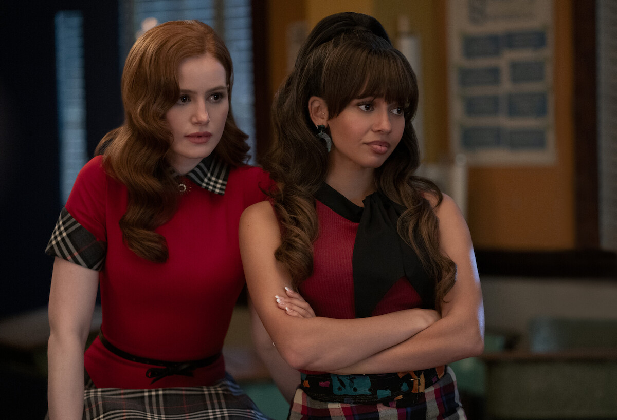 Madelaine Petsch as Cheryl Blossom and Vanessa Morgan as Toni Topaz stand together wearing red and plaid in Season 7 of ‘Riverdale.’