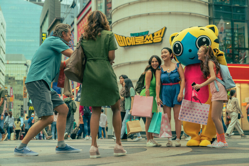 John Corbett as Dr Dan Covey, Lana Condor as Lara Jean Covey, Anna Cathcart as Kitty Covey, and Janel Parrish as Margot Covey taking pictures during their trip to Korea.
