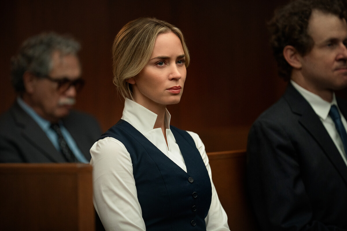 Emily Blunt as Liza sits in a courtroom.