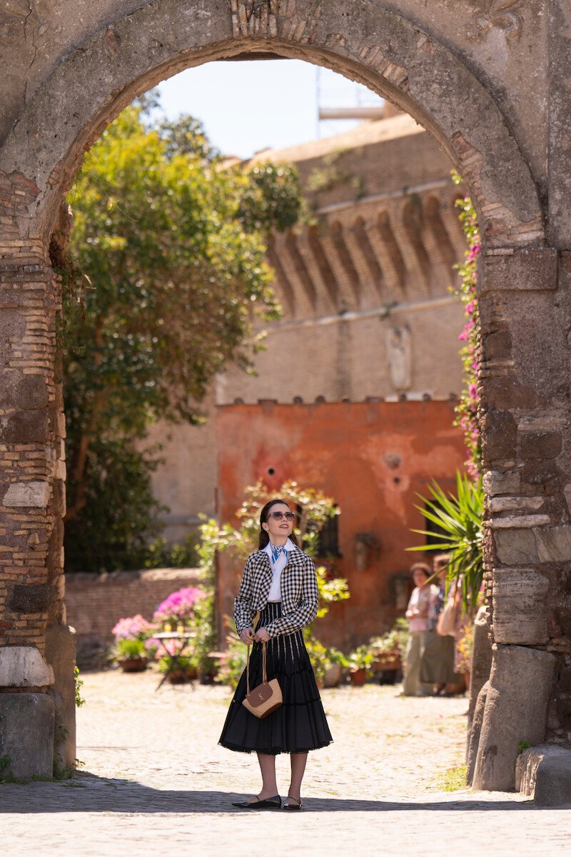 Lily Collins as Emily stands under a stone archway in Season 4 of 'Emily in Paris'
