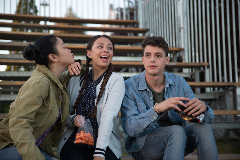 Lana Condor as Lara Jean, Janel Parish as Margot, and Israel Broussard as Josh sitting on bleechers.