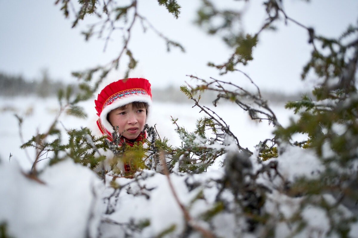 In a still image from the film ‘Stolen,’ actor Risten-Alida Siri Skum as Young Elsa wears a red hat and looks off camera in a snowy forested area.