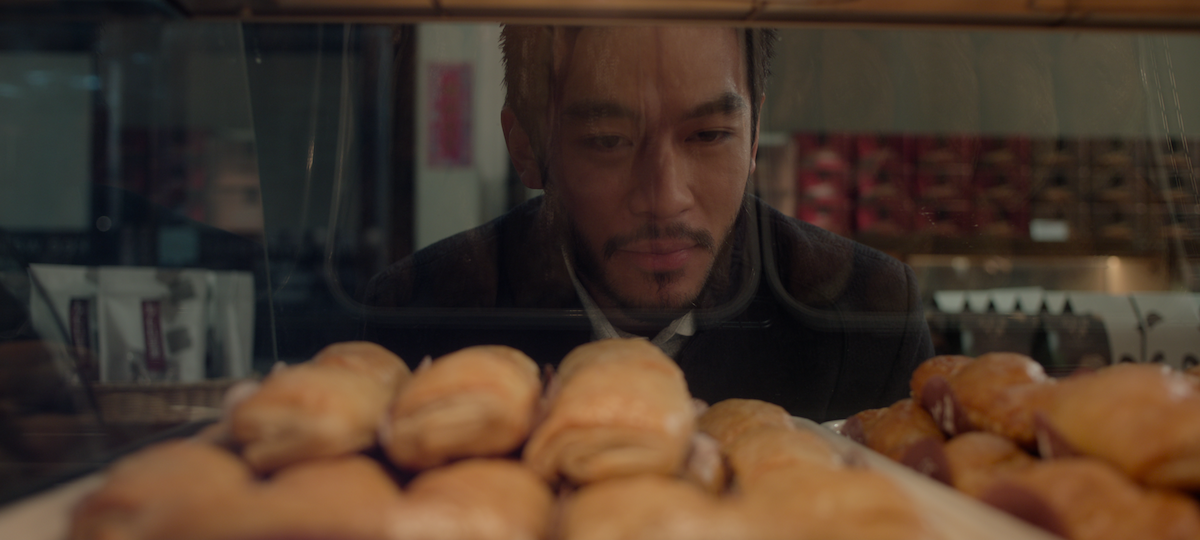 Justin Chien as Charles Sun looks through a bakery display case in season 1 of ‘The Brothers Sun’